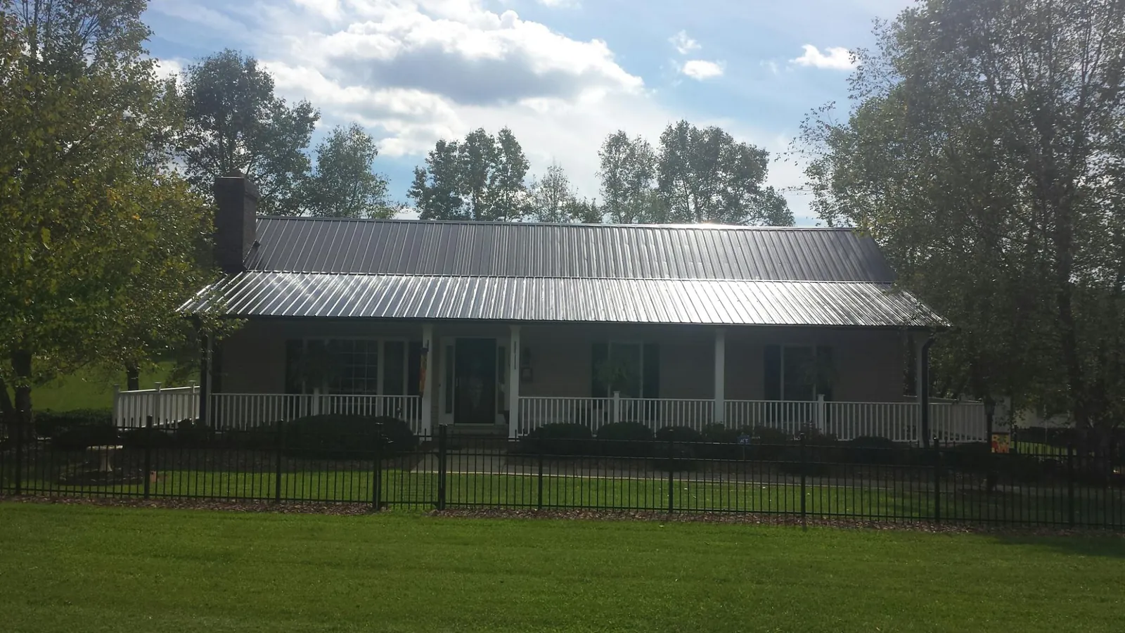 Gray metal roof on a brick ranch with a full width front porch — Gutter Guard Installation work by our crew in Flat Rock