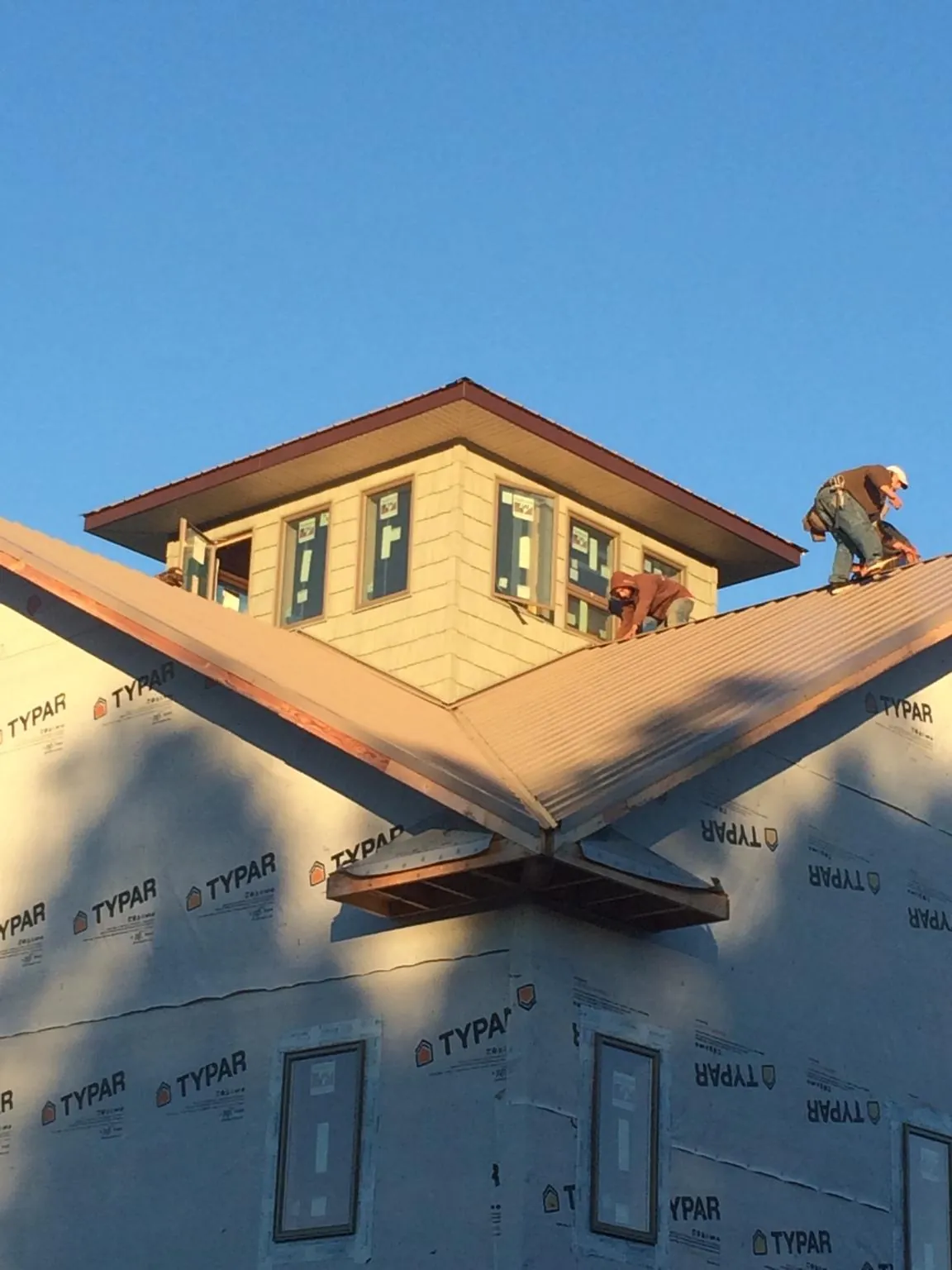 Roofers working around a rooftop cupola on a new metal roof at sunset — Roof Waterproofing in Flat Rock by Roofing Brothers